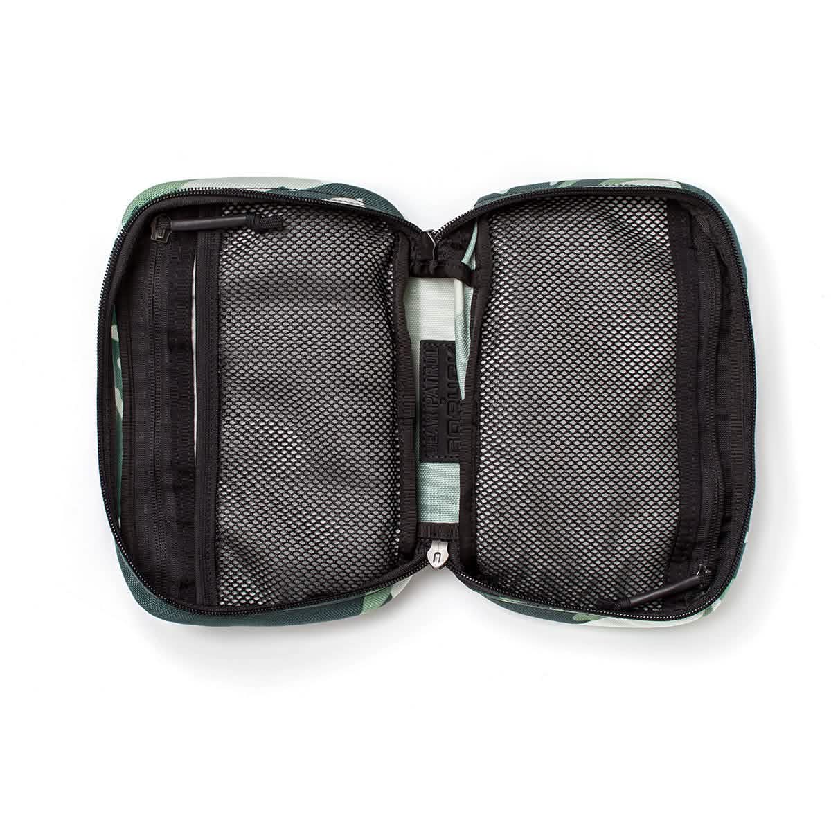 Introducing the GR1 Field Pocket x Gear Patrol by GORUCK: a sleek rectangular pouch featuring a distinctive Variegated Elephant Ear Camo pattern in dark green and black. The interior is equipped with mesh pockets and zippered compartments, ideal for your next Gear Patrol, ensuring your essentials stay organized while maintaining a discreet style.