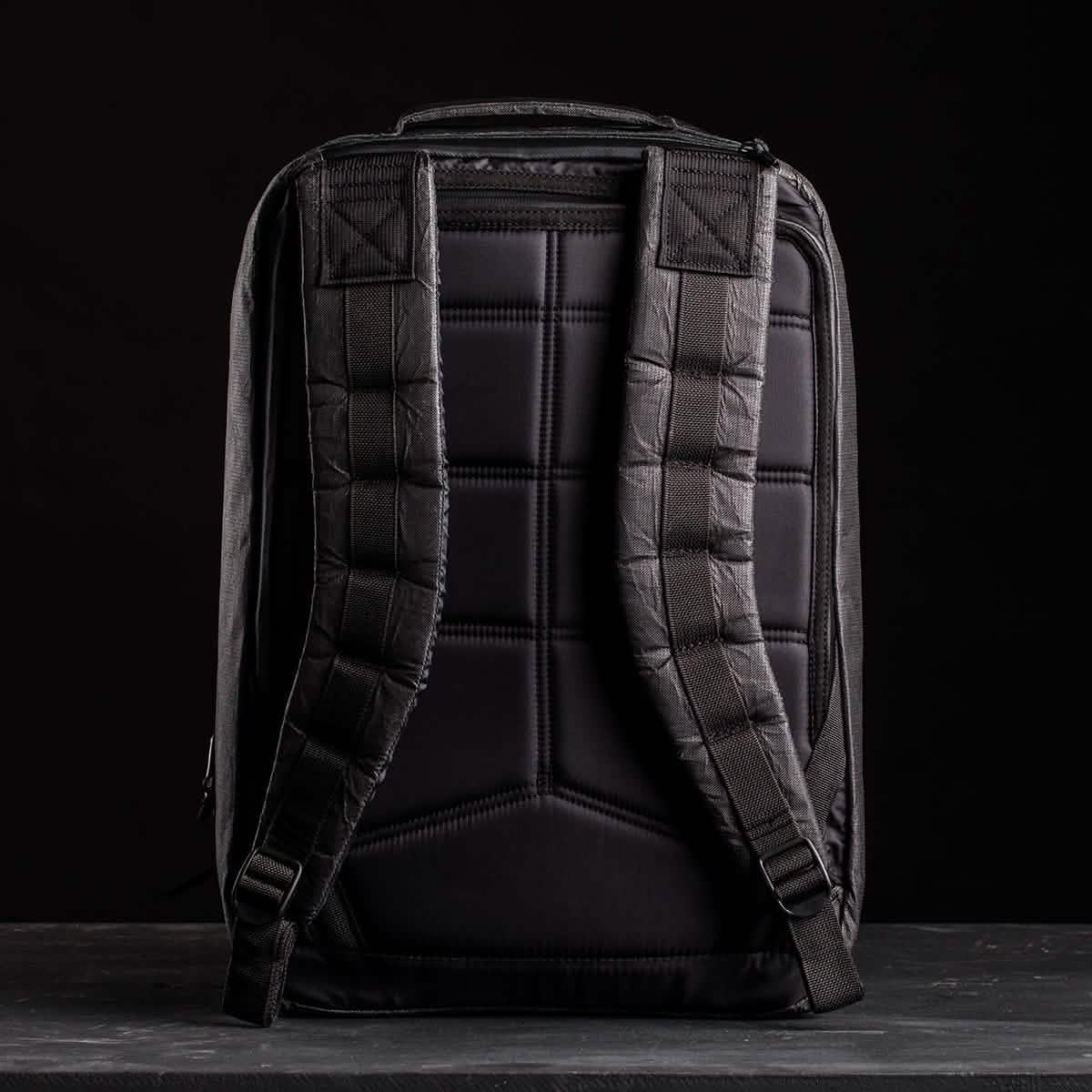 The GR2 USA x Carryology - Ultra Black is a black backpack with padded shoulder straps and back panel, made from durable Challenge Sailcloth, displayed against a dark background.