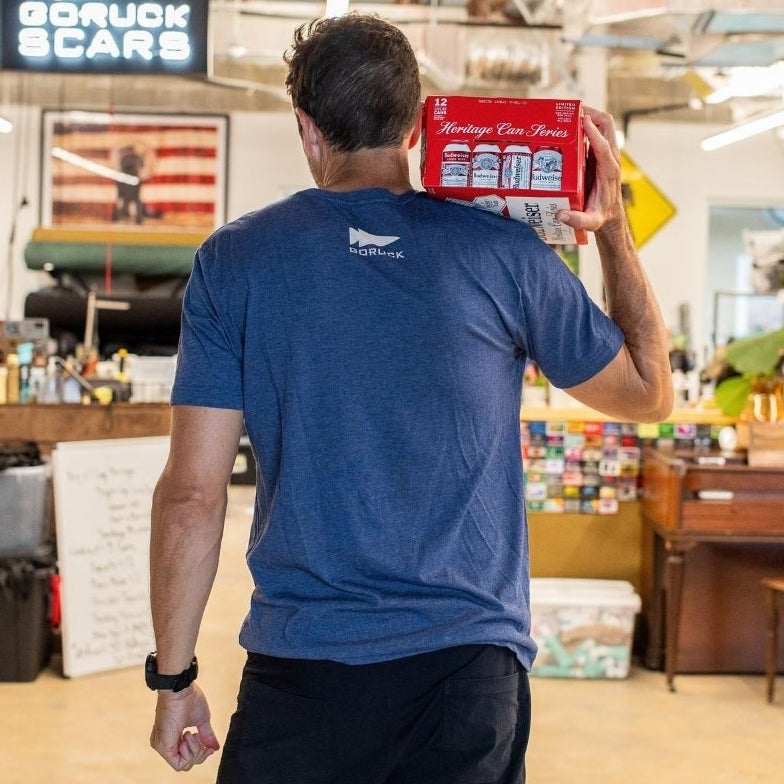 A man in a blue shirt holding an ACRT case on his shoulder stands in a casual, colorful indoor space.