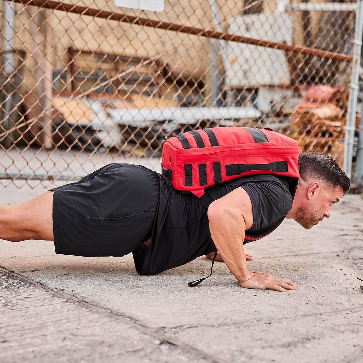 Man doing push-up outdoors with red GORUCK rucking backpack, fitness gear focus