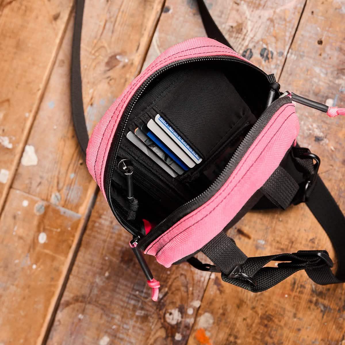 Open pink GORUCK ID card organizer pouch on wooden floor showing multiple cards inside