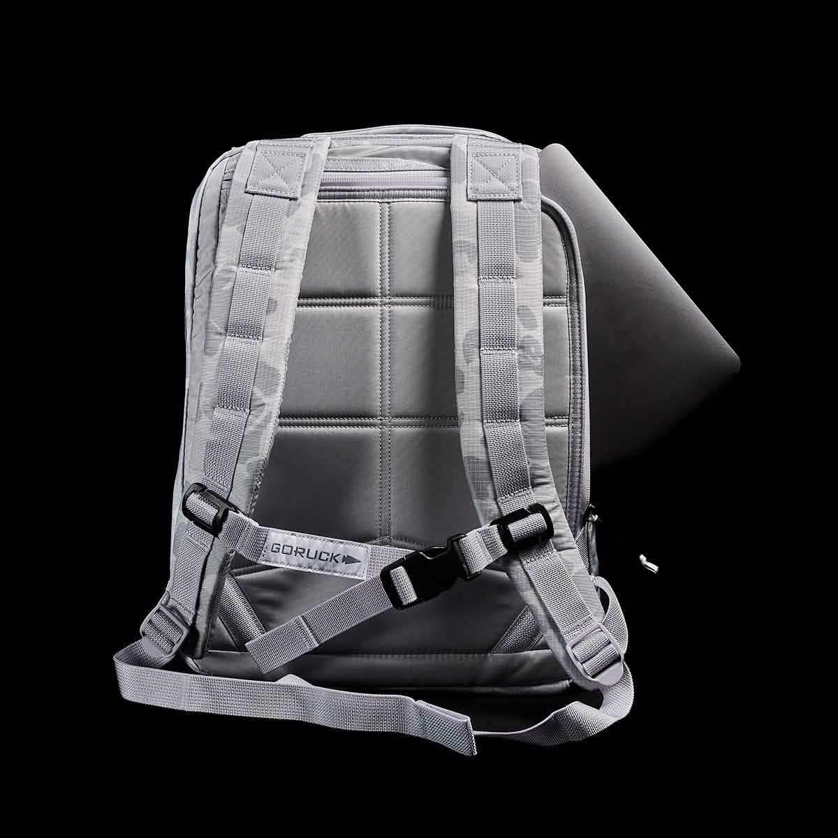 The GR0 - Ripstop ROBIC® is a gray, water-resistant backpack with padded straps and a laptop partially tucked into its back compartment—ideal for minimalist everyday carry.