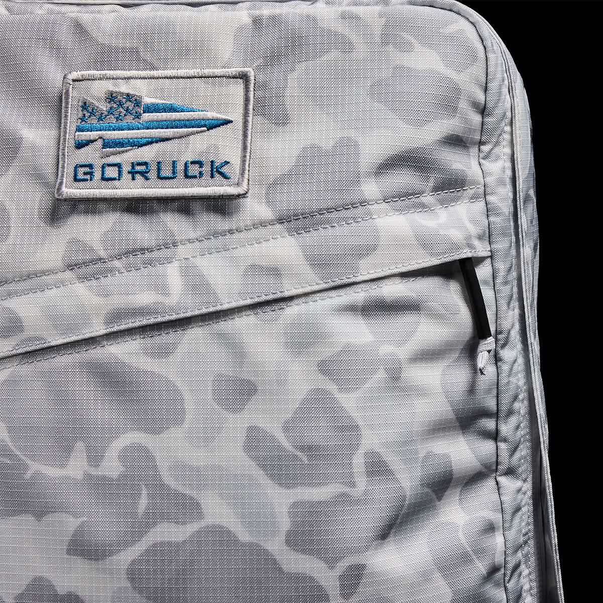 The GR0 - Ripstop ROBIC® is a gray camo, water-resistant backpack with a GORUCK patch featuring a blue spearhead and text—ideal for minimalist everyday carry.