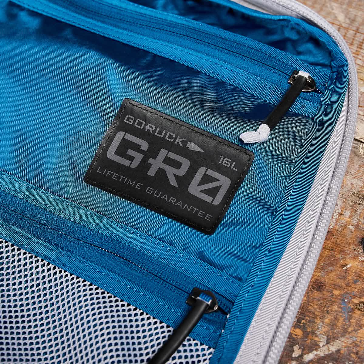 Close-up of a blue GR0 - Ripstop ROBIC® rucksack interior with zippered mesh pockets and a black logo patch—ideal as a water-resistant minimalist everyday carry backpack.
