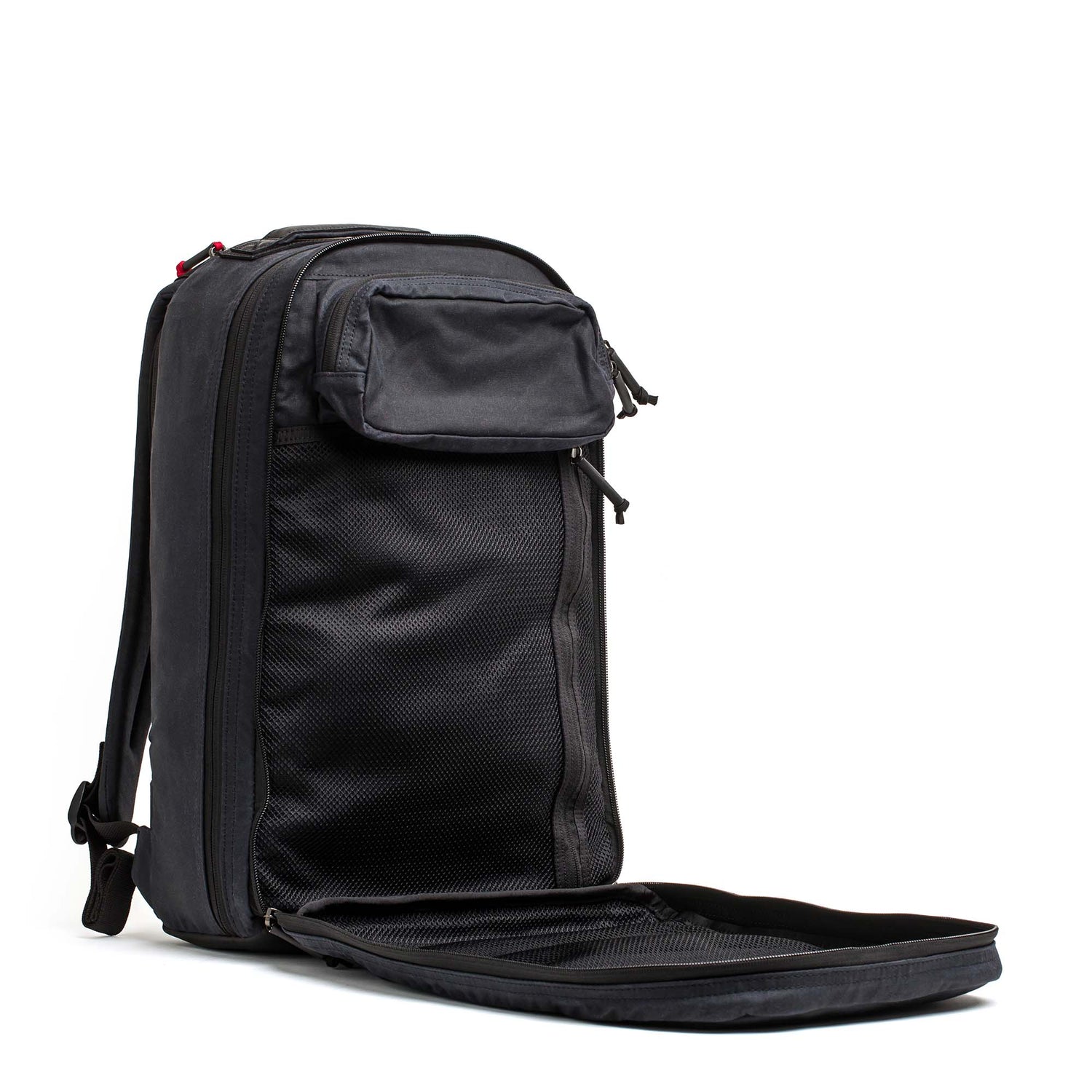 The Double Compartment Bullet Ruck - Heritage Waxed Canvas - 18L is shown open, displaying its front compartment with mesh pockets and an outer zippered pouch.