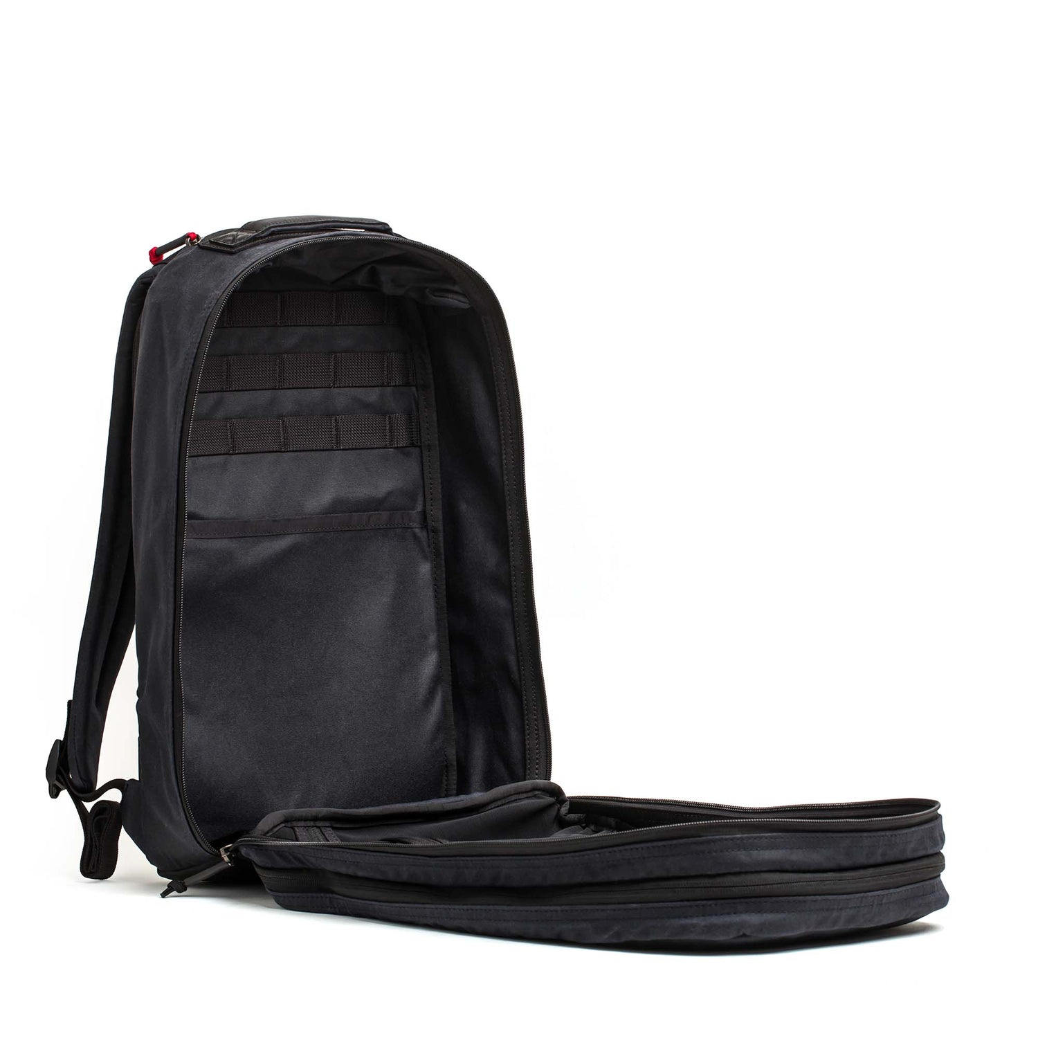 The Double Compartment Bullet Ruck - Heritage Waxed Canvas - 18L is unzipped and open, showcasing its spacious, organized interior against a white background.