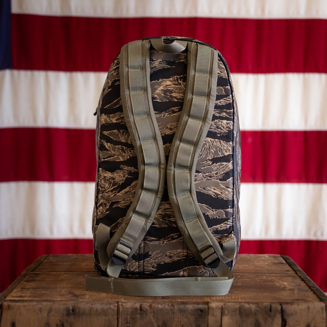 The Tiger Stripe Robic Bullet - Built by Scars rests on a wooden table with an American flag background.