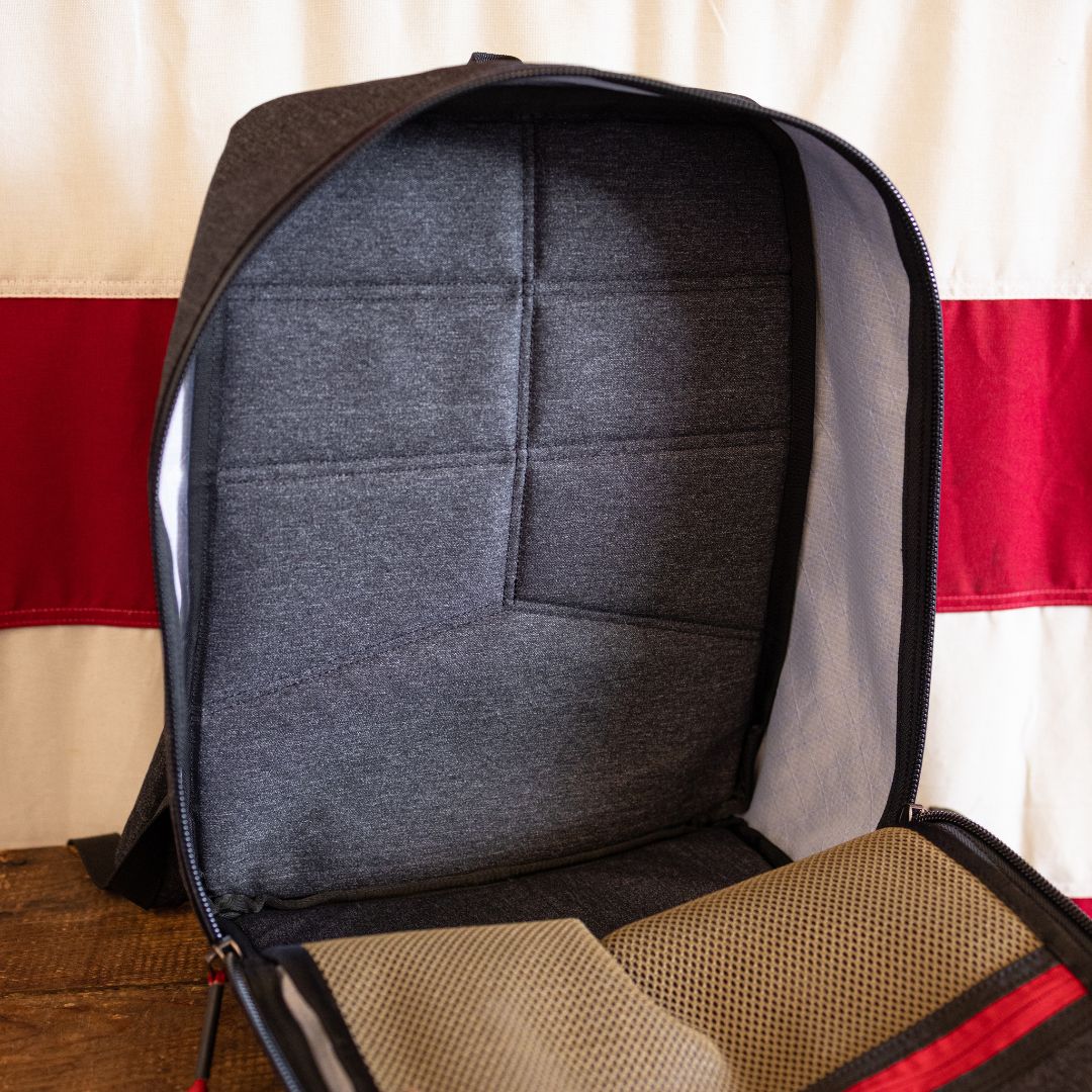 Open handmade dark gray backpack showing an interior with a padded back panel and mesh pockets.