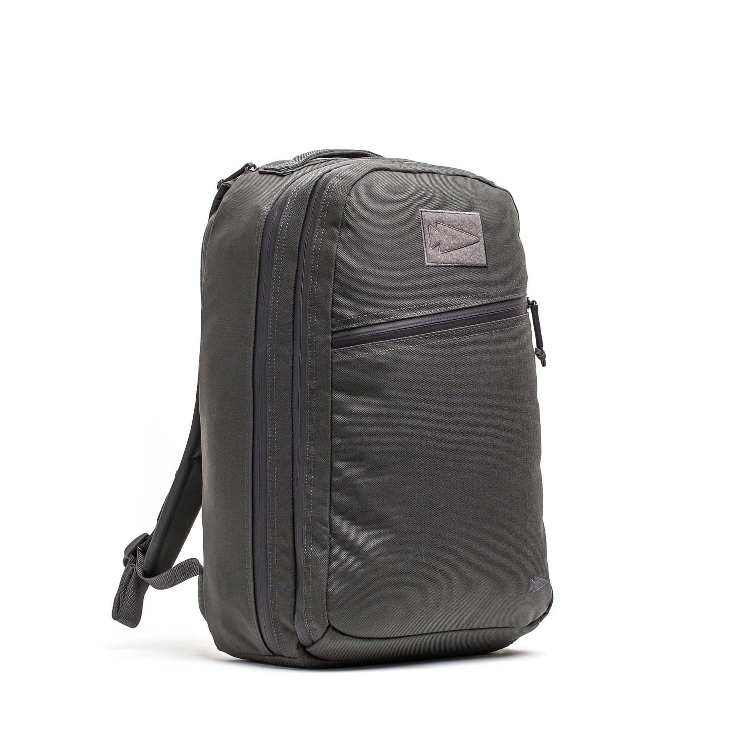 The Double Compartment Bullet Ruck - Ballistic Nylon Cordura - 18L is a dark gray travel backpack with a front zipper pocket, side strap, rectangular front patch, and a bombproof laptop compartment for secure storage.