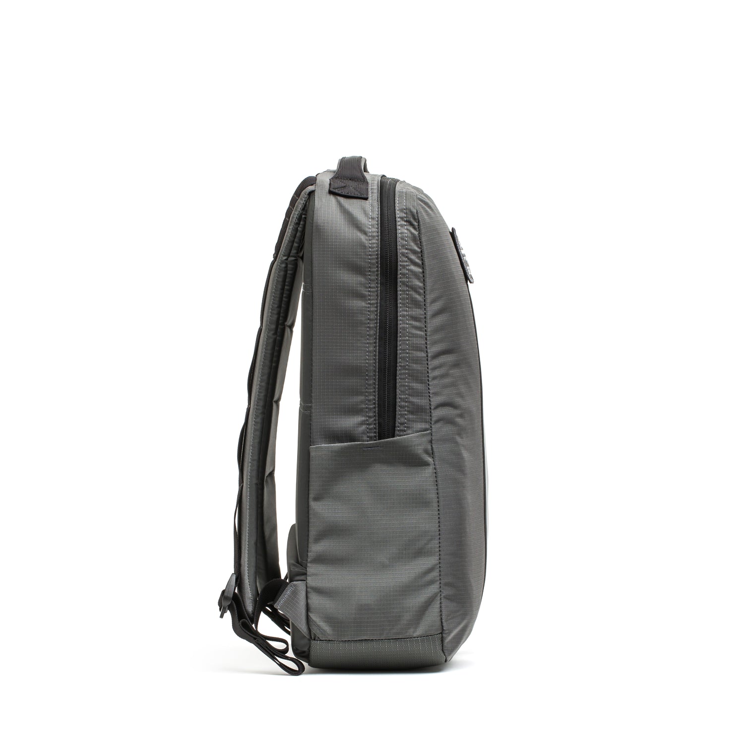 The Basic Rucker® in gray is shown from the side, featuring padded straps and a front zip pocket for convenient storage.