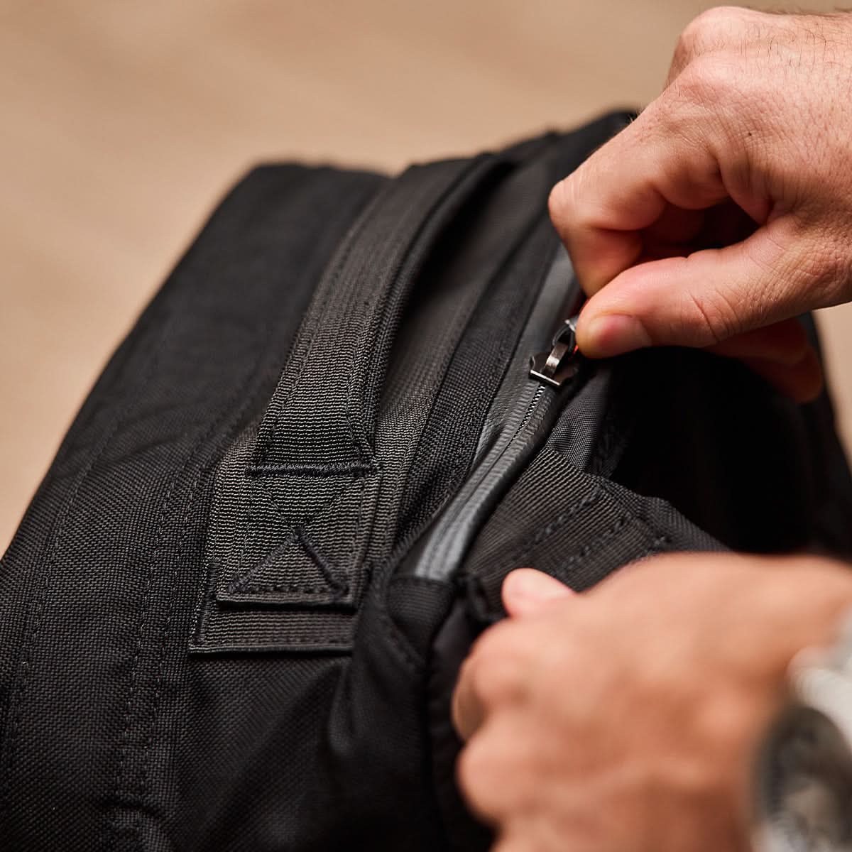 Close-up of hands unzipping the black GR1 USA - Ballistic Nylon Cordura (The Original Ruck), highlighting durable zipper and fabric details crafted from Special Forces grade materials.