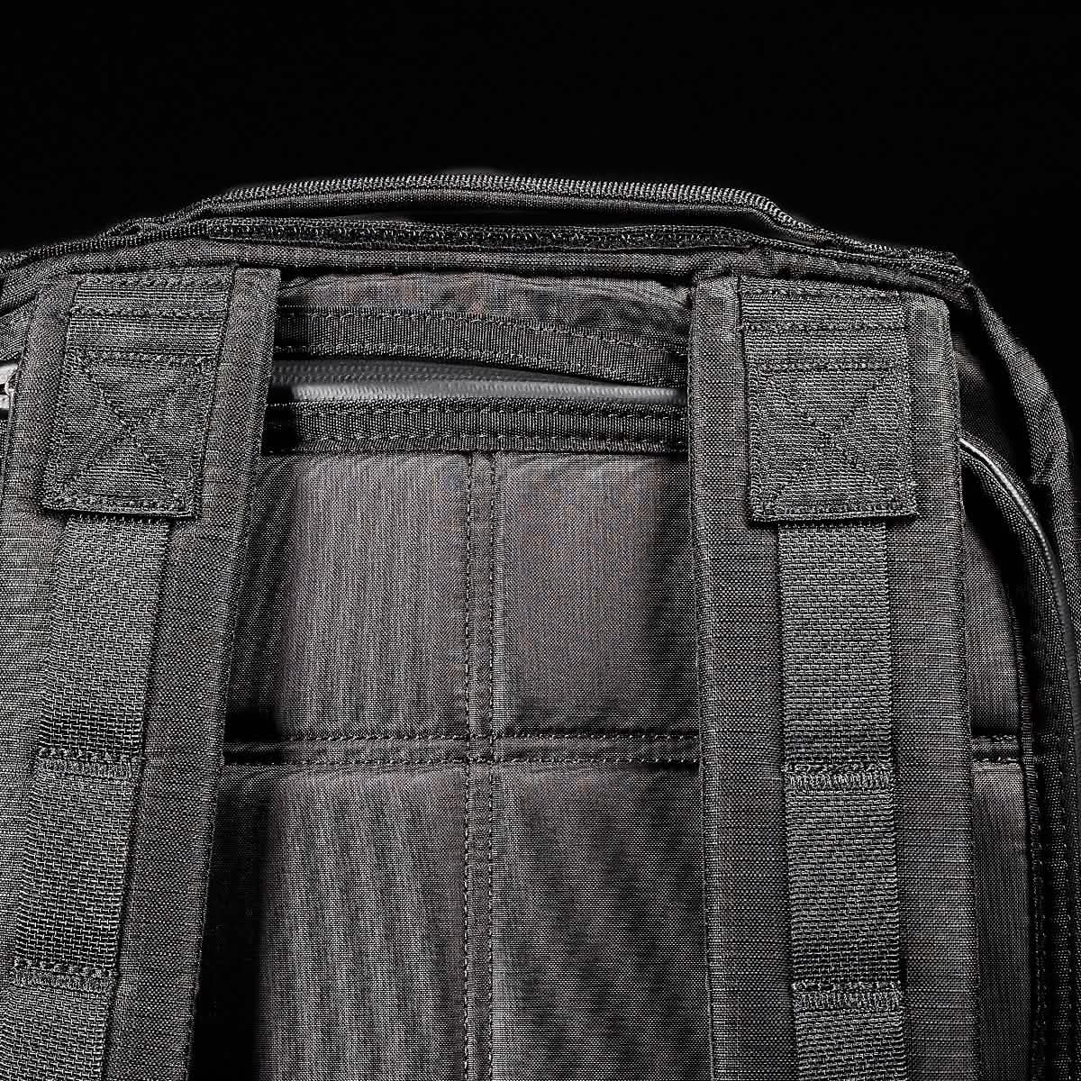 Close-up of the back of the black GR0 - Ripstop ROBIC® water resistant backpack with padded shoulder straps, set against a black background—ideal for minimalist everyday carry.