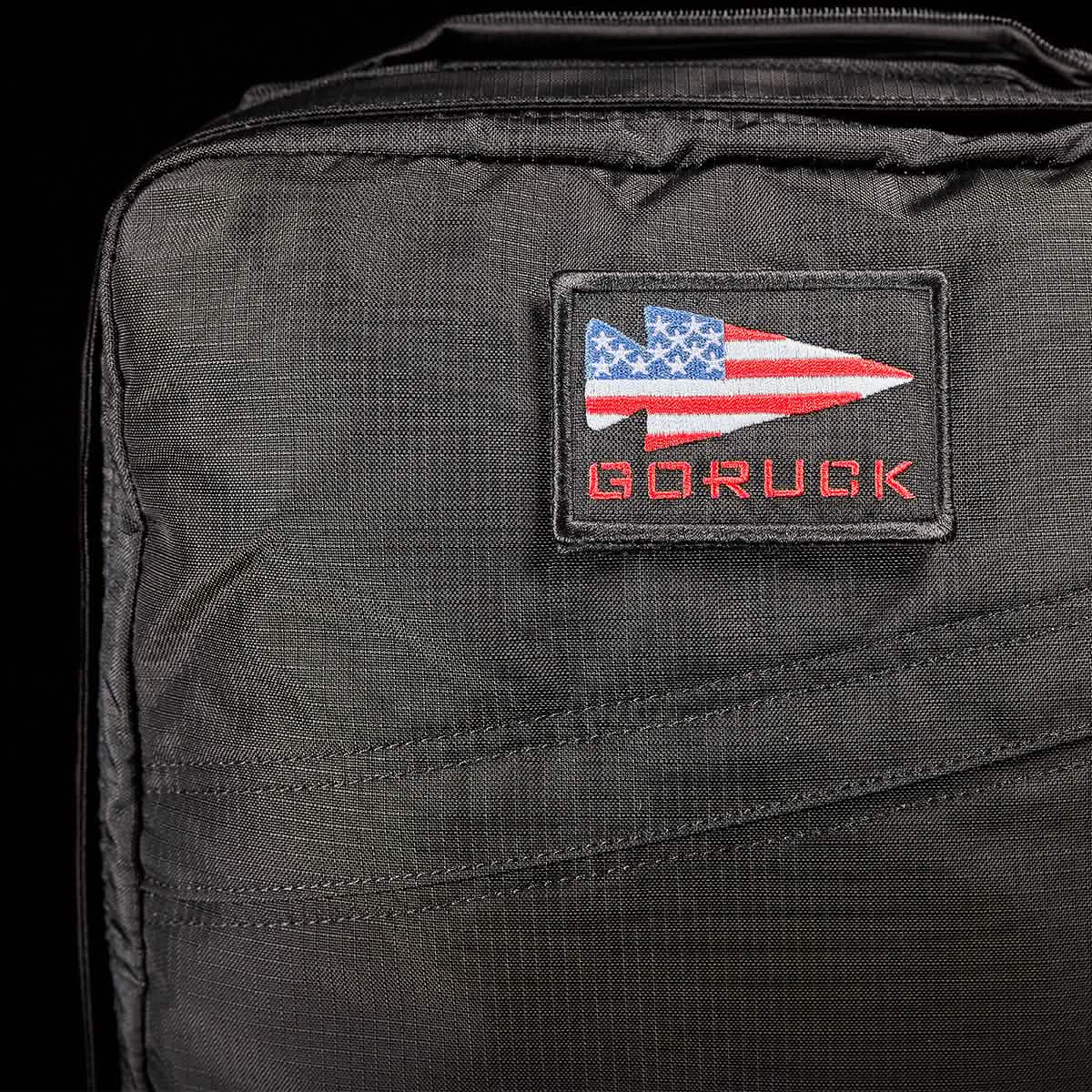 Close-up of the GR0 - Ripstop ROBIC®, a black, water resistant backpack with a GORUCK patch featuring a spearhead and American flag—ideal for minimalist everyday carry.