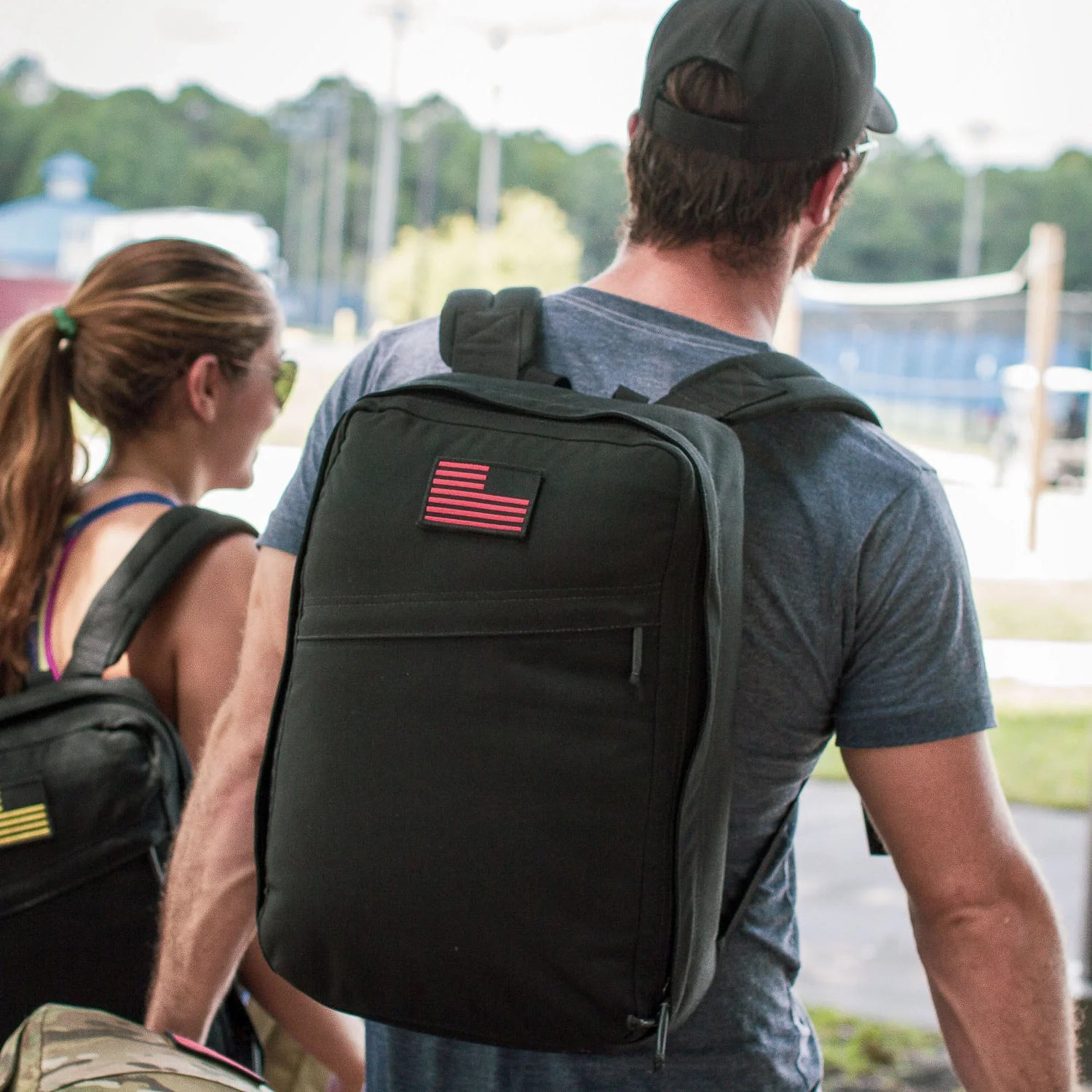 Man and woman outdoors carrying black GORUCK backpacks with American flag patches