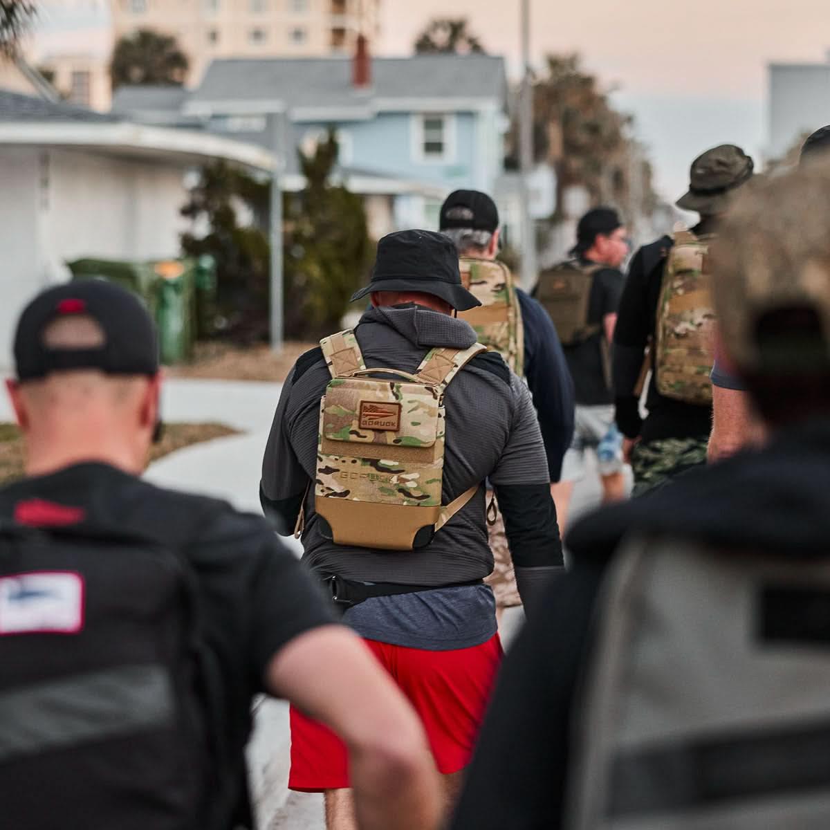 Group of people walking outdoors wearing camouflage GORUCK rucking backpacks and casual athletic clothing