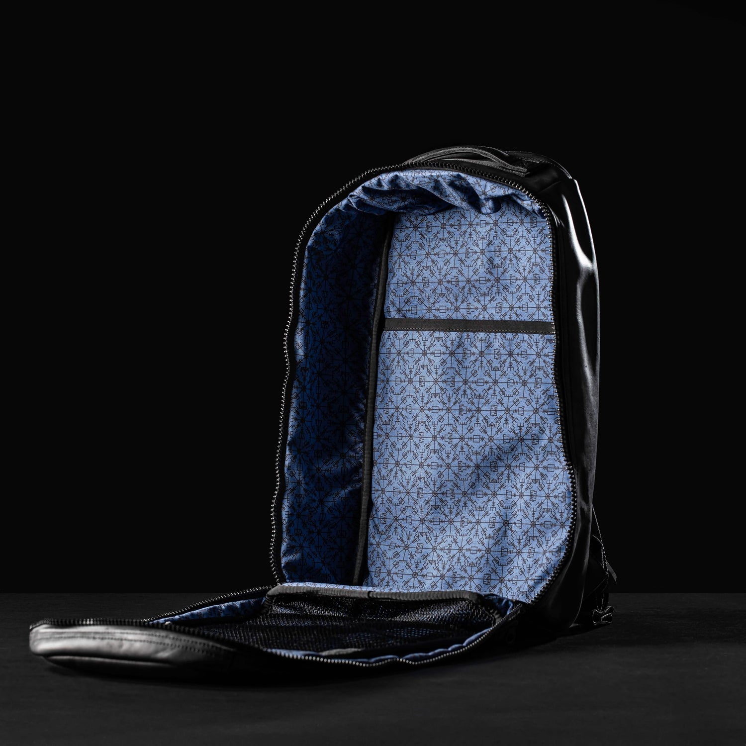 Open black leather GORUCK Bullet 15L backpack showing blue patterned interior and mesh pocket on dark background