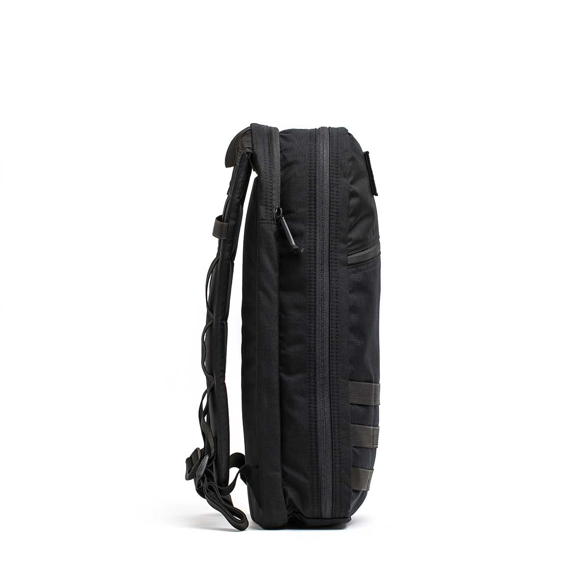 The Bullet Ruck USA Throwback is a sleek black daypack with visible zippers, an adjustable shoulder strap, and durable CORDURA construction, shown from the side.