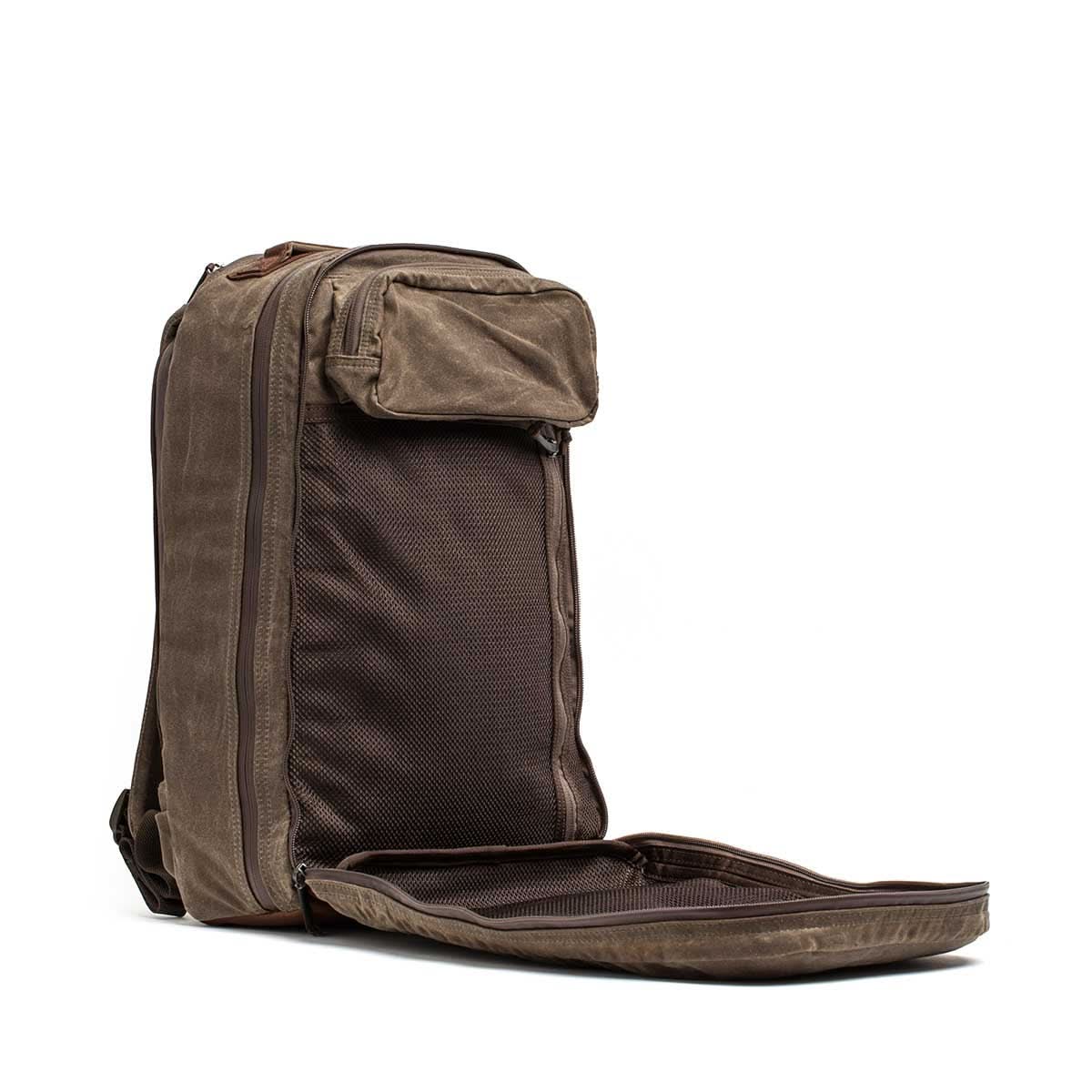 A Waxed Canvas 18L Bullet Ruck backpack in brown with its front compartment unzipped, showing a large mesh pocket inside.