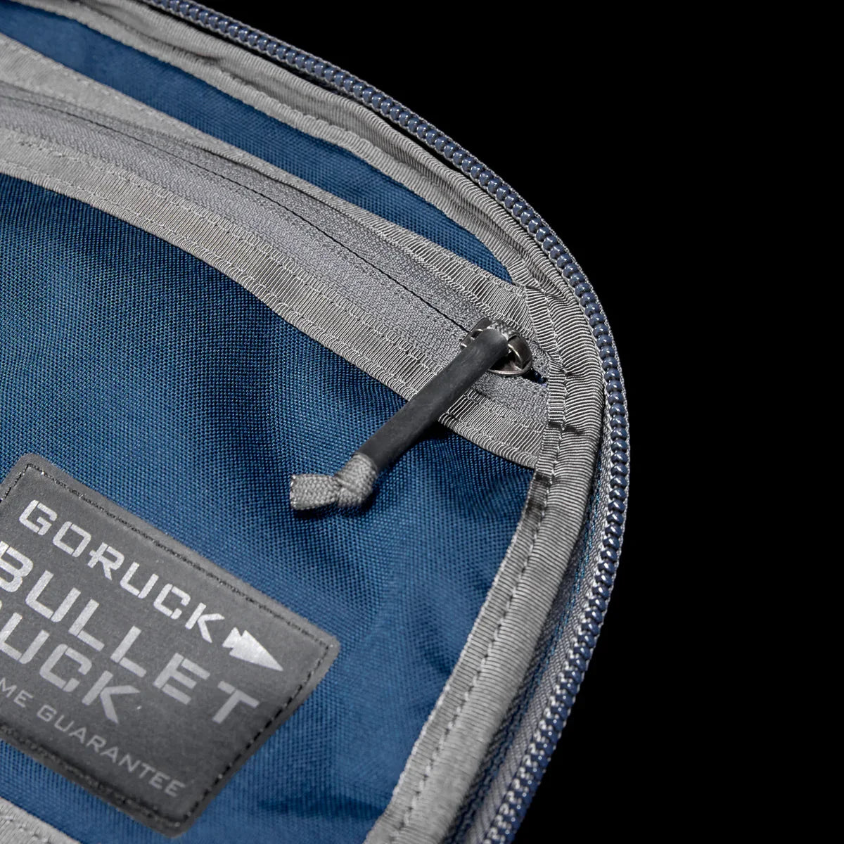Close-up of GORUCK Bullet Ruck Classic pack's dark sea blue Cordura fabric and Armor Grey zipper with pull tab