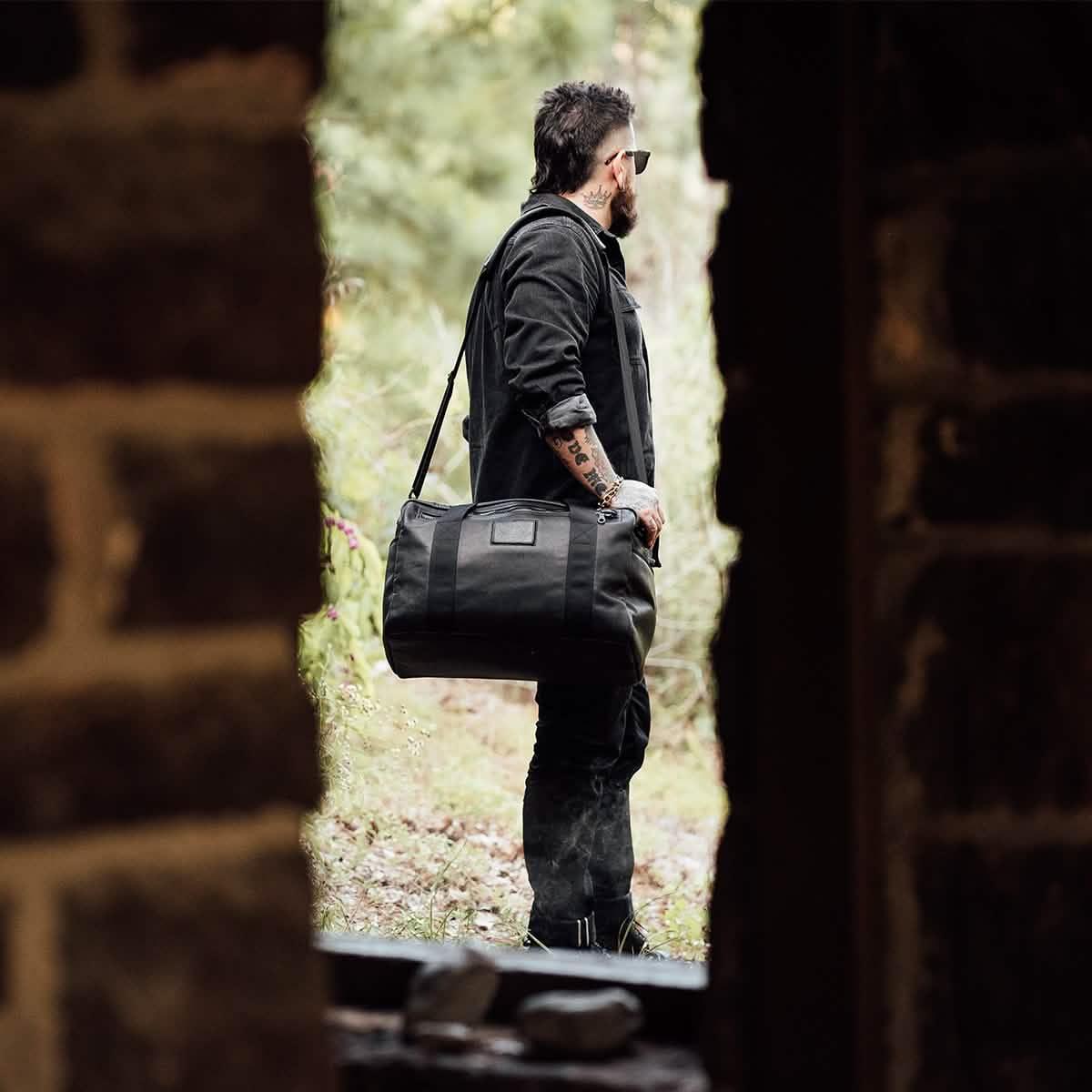 Man carrying GORUCK black kit bag outdoors, rugged gear for rucking and adventure.