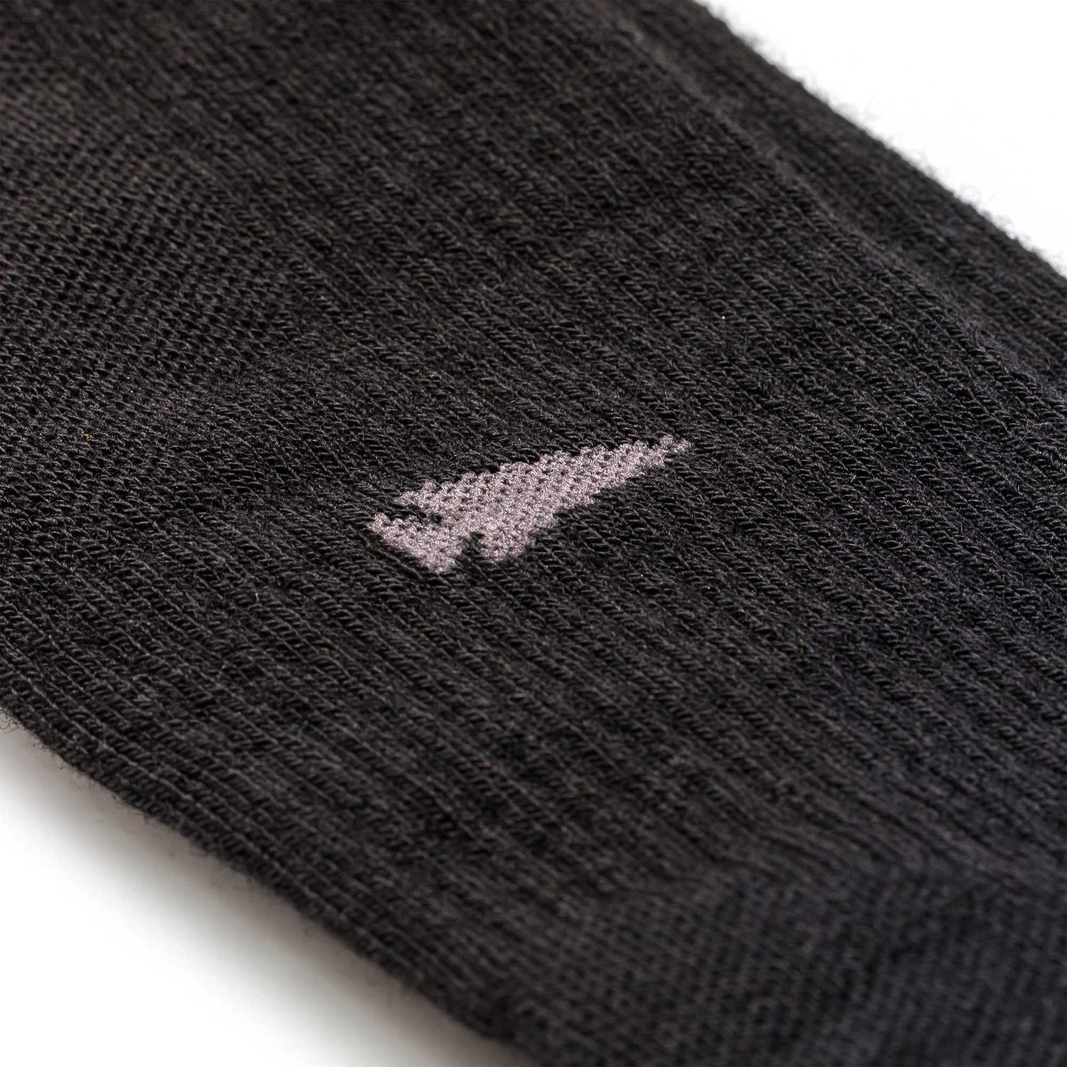 Close-up of Merino Compression Socks in black, featuring a small light gray arrow design stitched on the side.