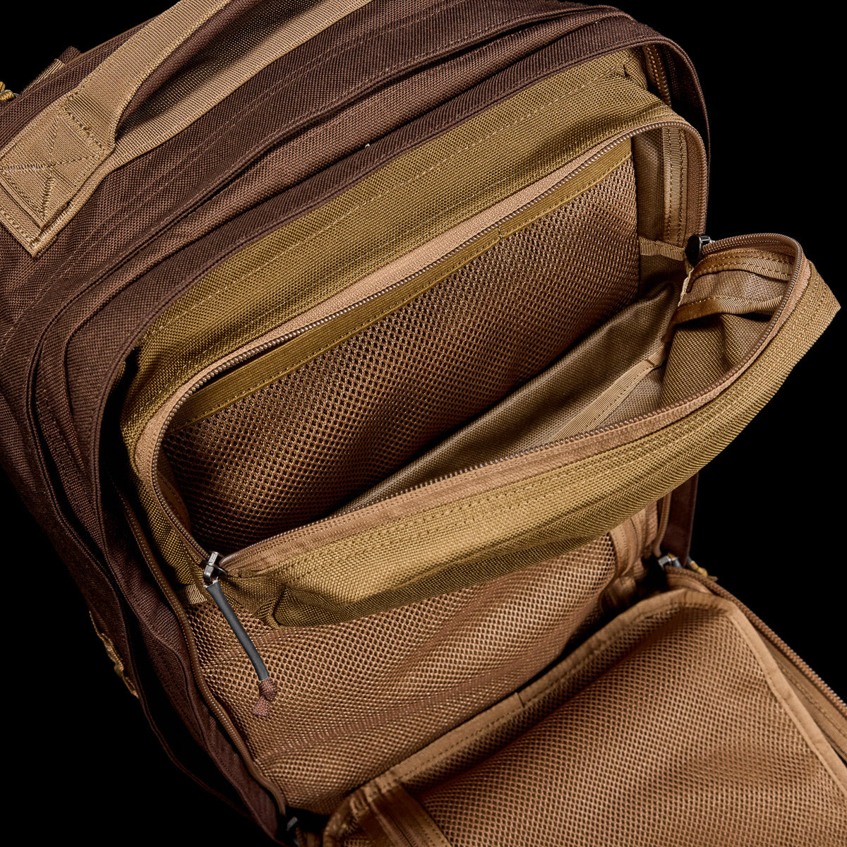 Open brown tactical GORUCK rucksack showing interior mesh pockets and zippers for gear organization