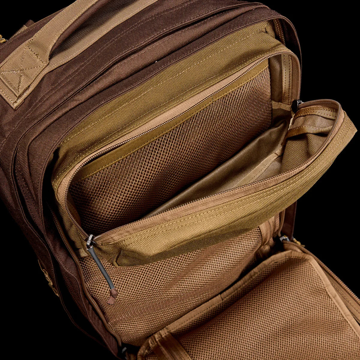 Open brown tactical GORUCK rucksack showing interior mesh pockets and zippers for gear organization