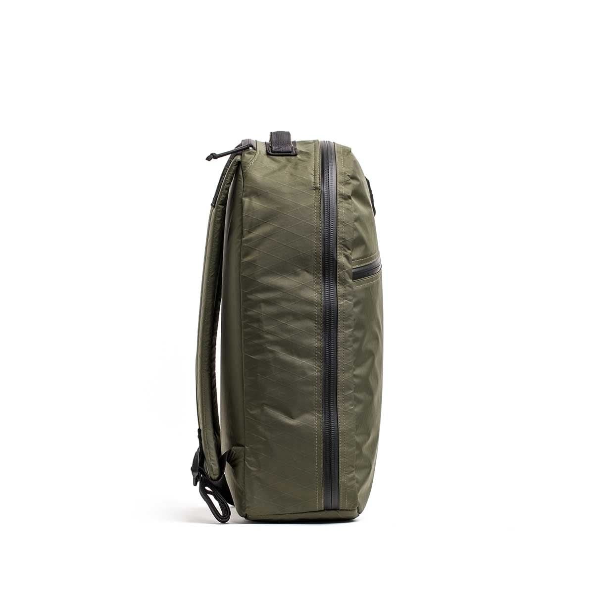 Side view of the green Bullet X-PAC daypack featuring a vertical AquaGuard zipper and a single shoulder strap, shown on a white background.