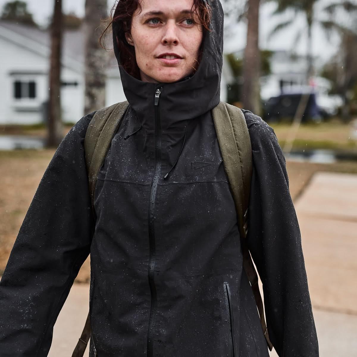 Person wearing GORUCK waterproof jacket and backpack in light rain outdoors