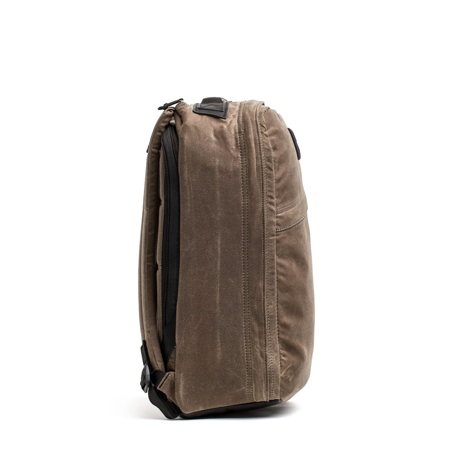 A side view of the GR1 USA - Heritage by GORUCK showcases its robust fabric and sleek design. Emphasizing practicality and user convenience, the zipper and shoulder straps stand out. Made from waxed duck canvas, this rucksack is set against a simple white background.