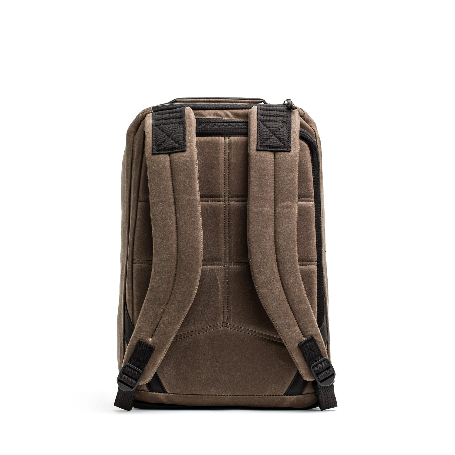 Back view of the GORUCK GR1 USA - Heritage rucksack in brown featuring black accents. Made from waxed duck canvas, it includes padded shoulder straps, reinforced stitching, and a textured surface. This retro design presents a sturdy appearance, ideal for everyday use or travel.