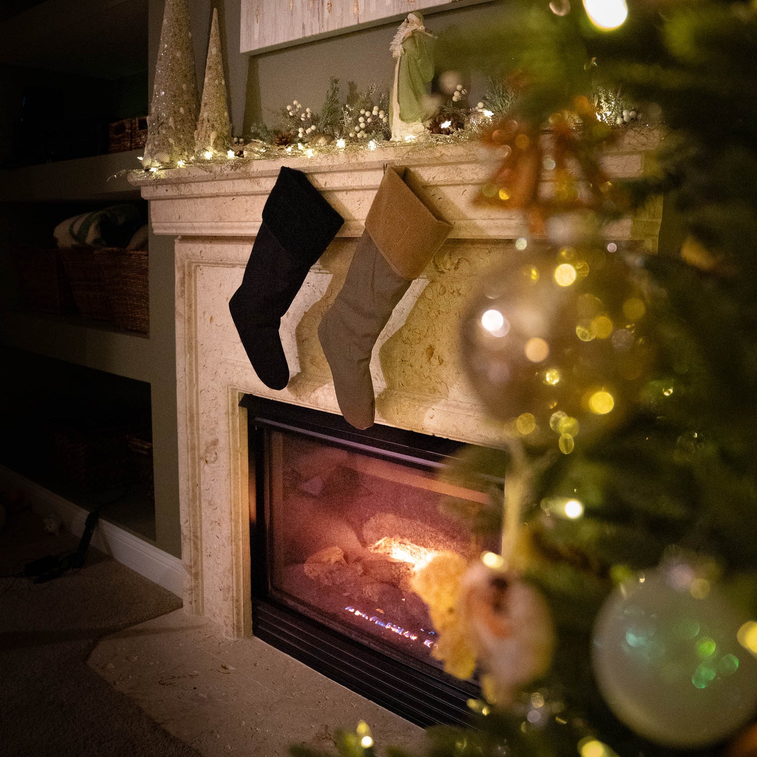 Tough Stockings hang on a decorated mantel above a glowing fireplace, featuring durable Cordura paracord accents for charm and strength, as ornaments sparkle on the nearby Christmas tree.