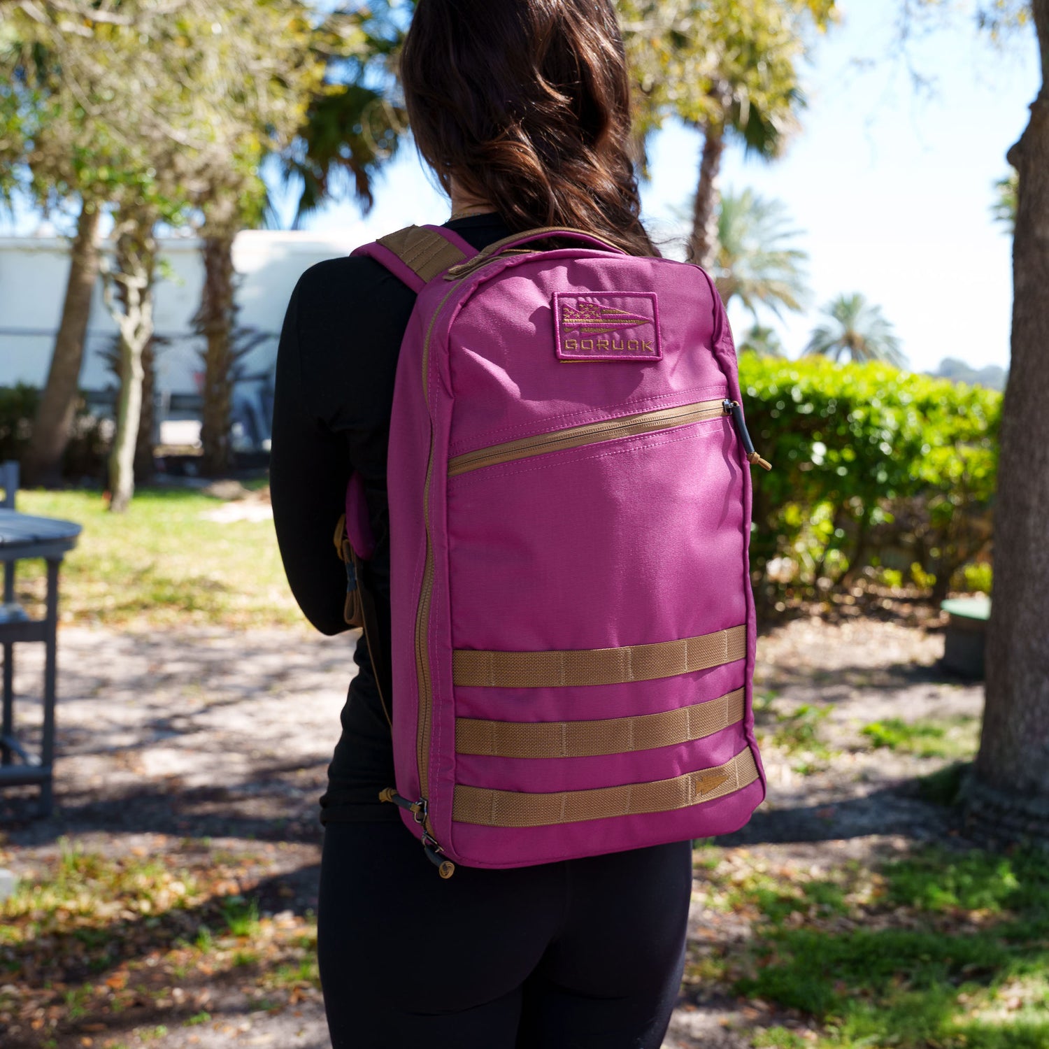 A person stands outdoors with their back to the camera, wearing a bright pink Bullet Ruck Classic - Ballistic Nylon Cordura 15L daypack.