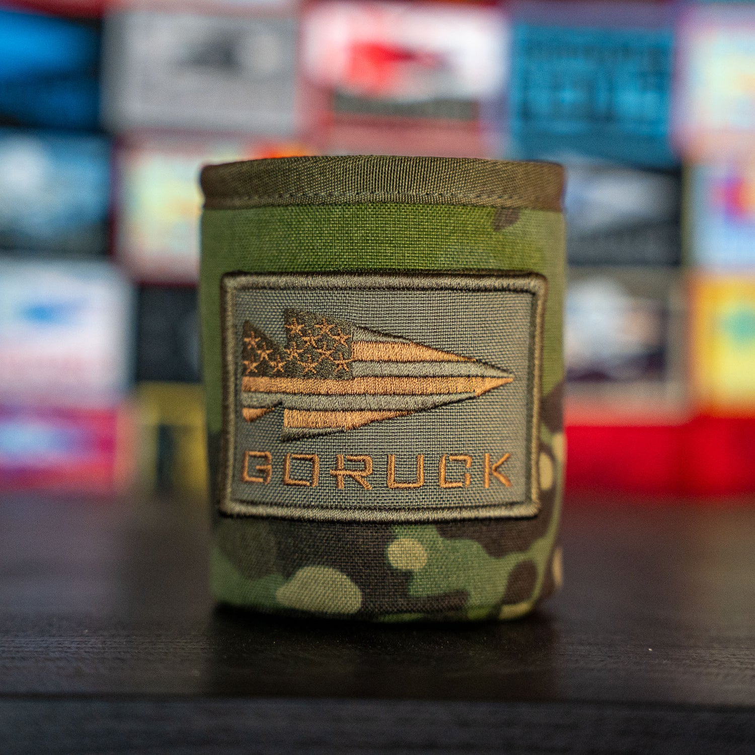 The Ballistic Beer Jacket is a camouflage sleeve drink jacket with a GORUCK patch featuring a stylized American flag and arrow—making it the perfect rugged beer koozie for your next adventure.