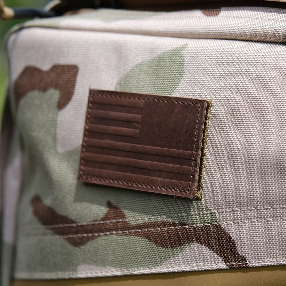 Close-up of the Rucker 4.0 in camouflage, featuring a brown leather patch with a minimalist American flag—ideal for rucking and built to securely hold your Ruck Plates.