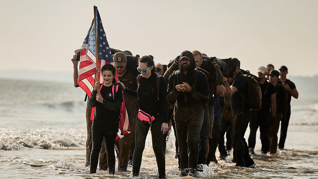 A group of people walking in the water with a flag.