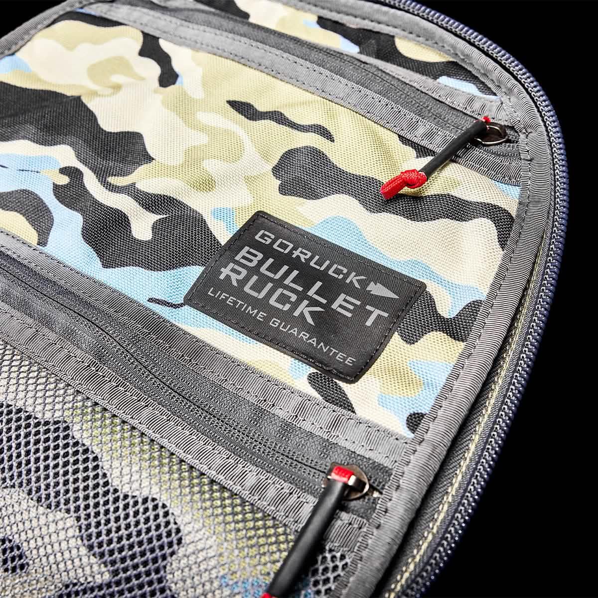 GORUCK Bullet Ruck gear with Everglades camo featuring zippered compartments and lifetime guarantee tag