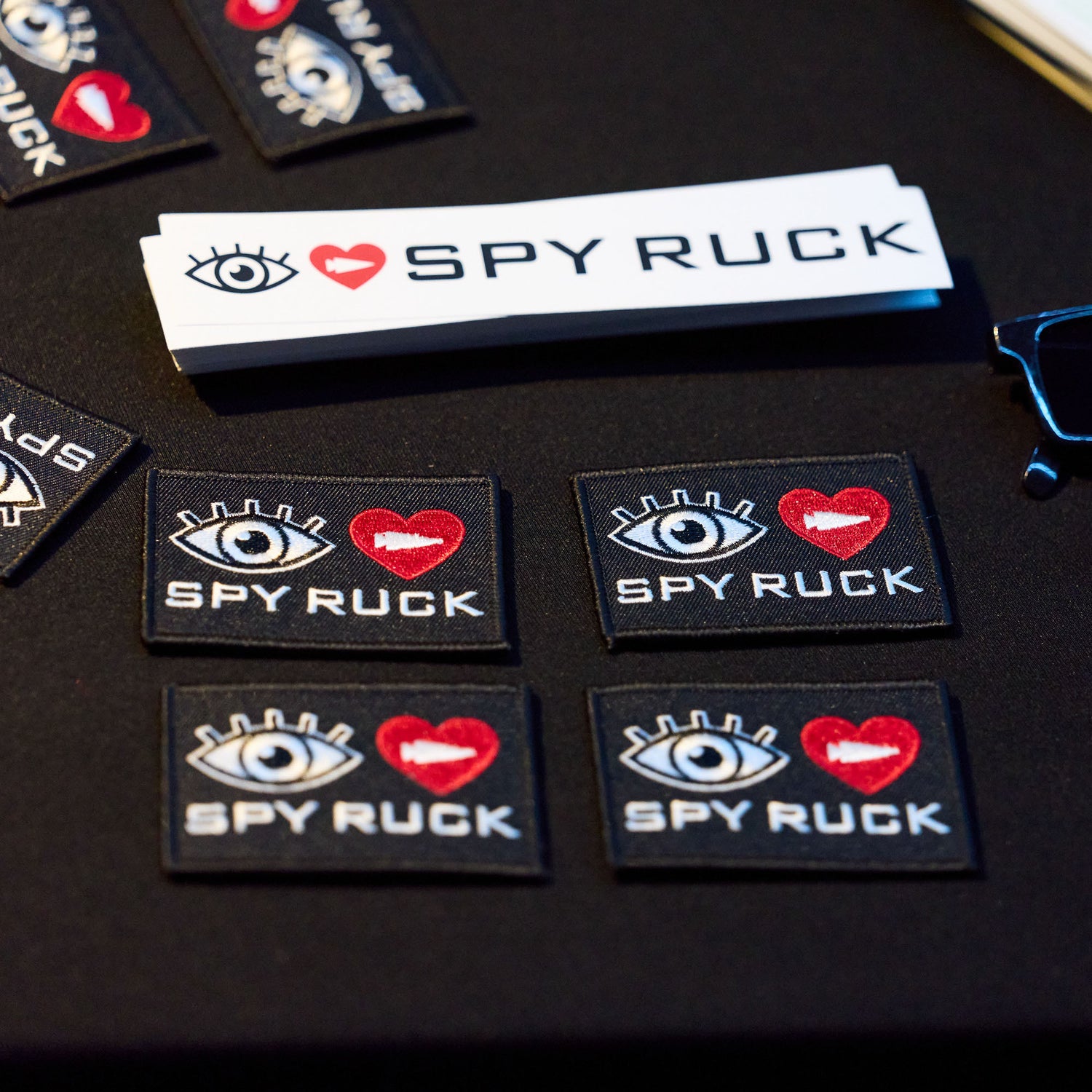 The Patch - Eye Heart Spy Ruck features bold eye and heart graphics on a sleek black surface, capturing the spirit of espionage for fans of spy gear and covert operations.