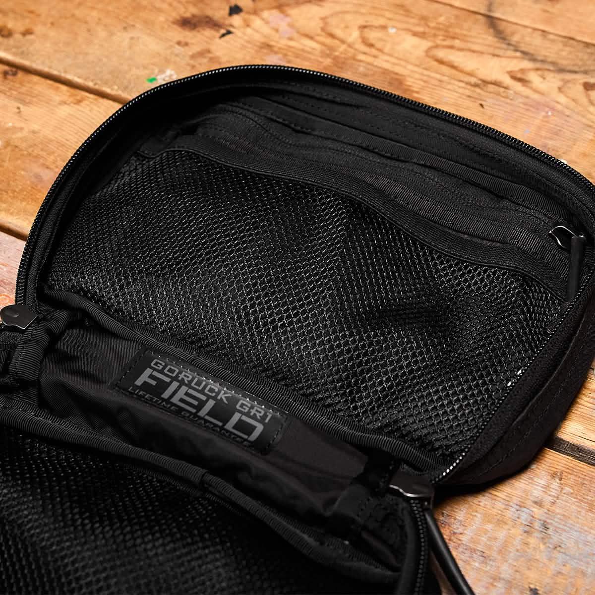 GORUCK GR1 Dyneema black field pocket open on wooden surface, mesh organizer visible