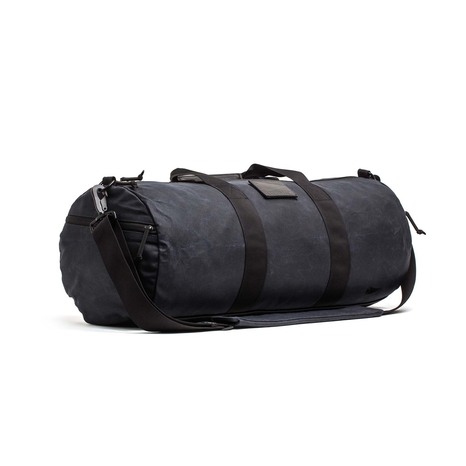 The Gym Bag - Waxed Canvas features handles and an adjustable shoulder strap, made from durable black waxed canvas and shown against a white background.