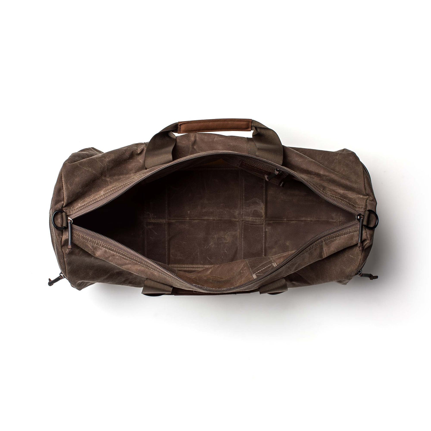 Top view of an empty brown Gym Bag - Waxed Canvas with the zipper open, revealing its spacious interior and leather handles.
