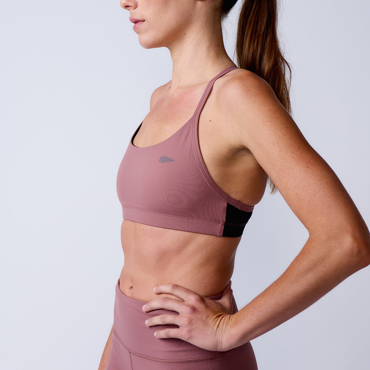 Woman in a mauve Stealth Bra - ToughFlex and leggings stands sideways against a plain light background.