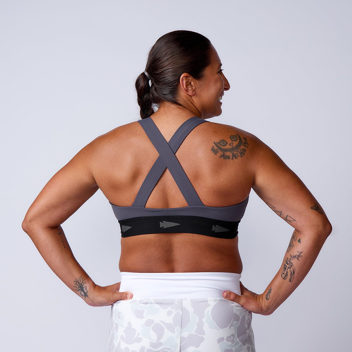 A tattooed woman poses from the back, wearing gray sports bra and Women’s Training Shorts - ToughStretch.