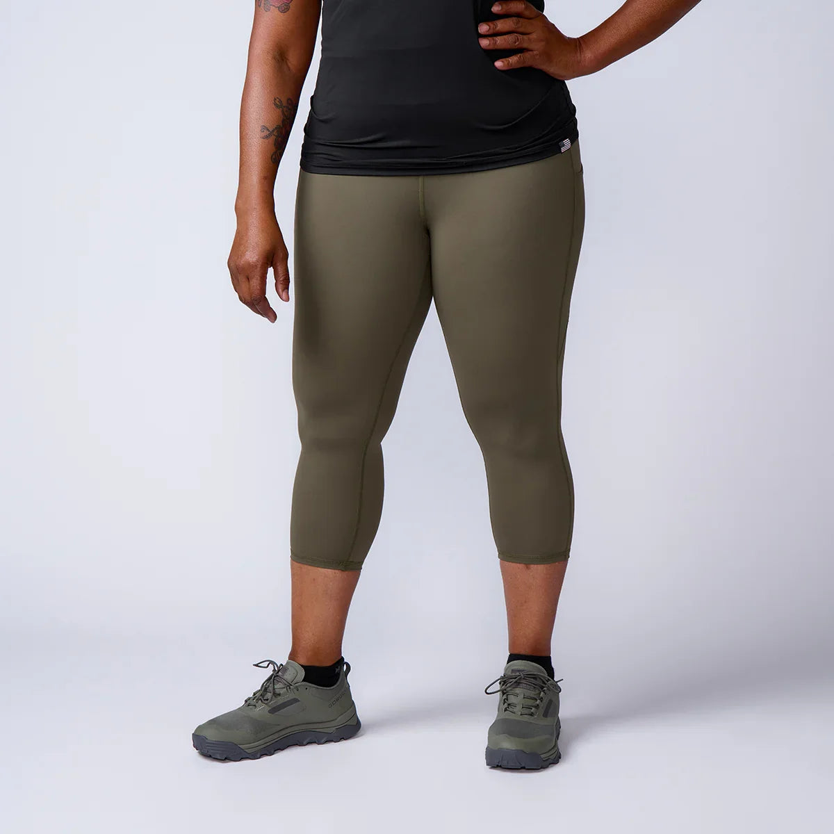 GORUCK olive green rucking leggings and athletic shoes on woman, studio background