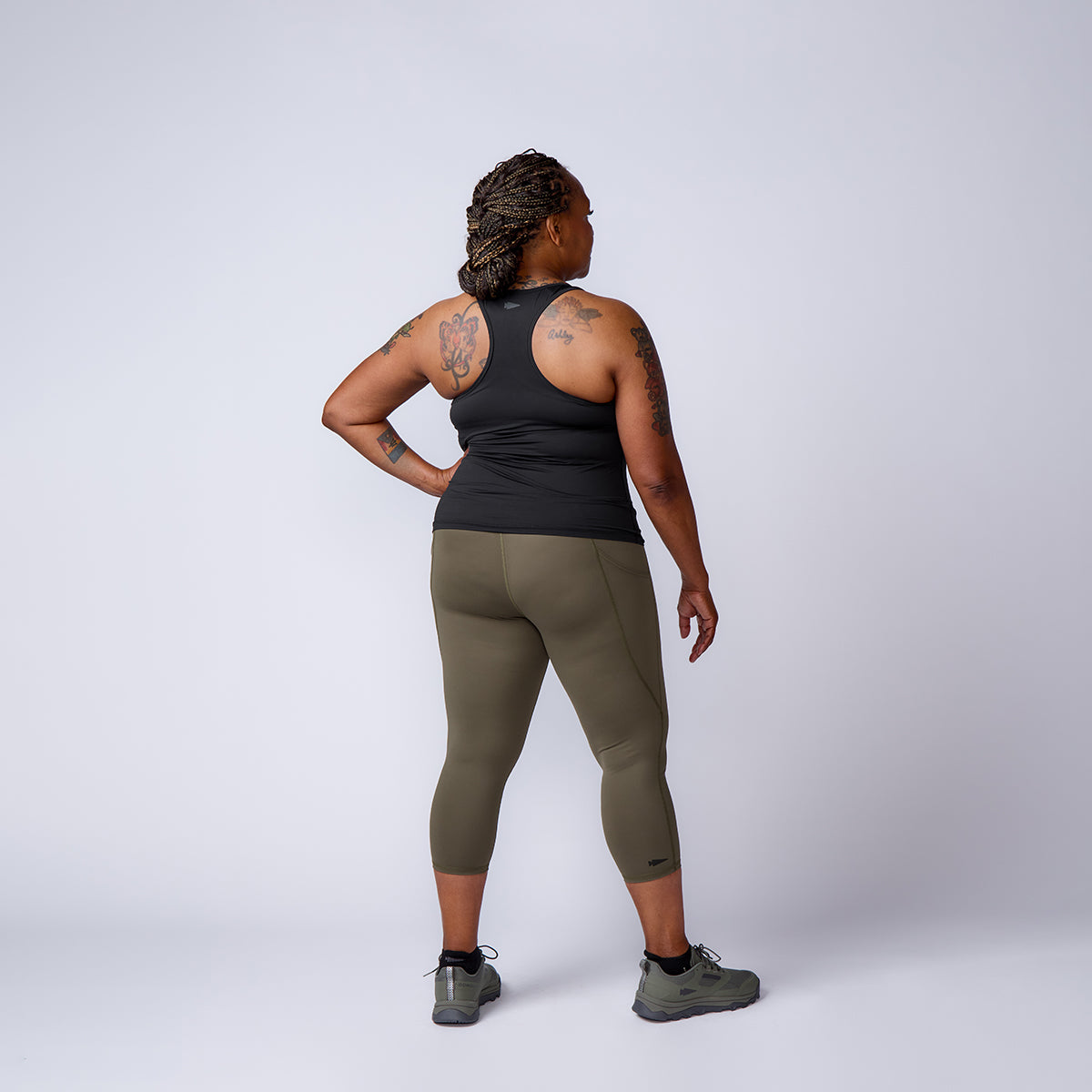 Person in athletic wear stands with back to camera, hand on hip, showcasing Women’s Training Leggings Pocket - ToughFlex against a plain light background.