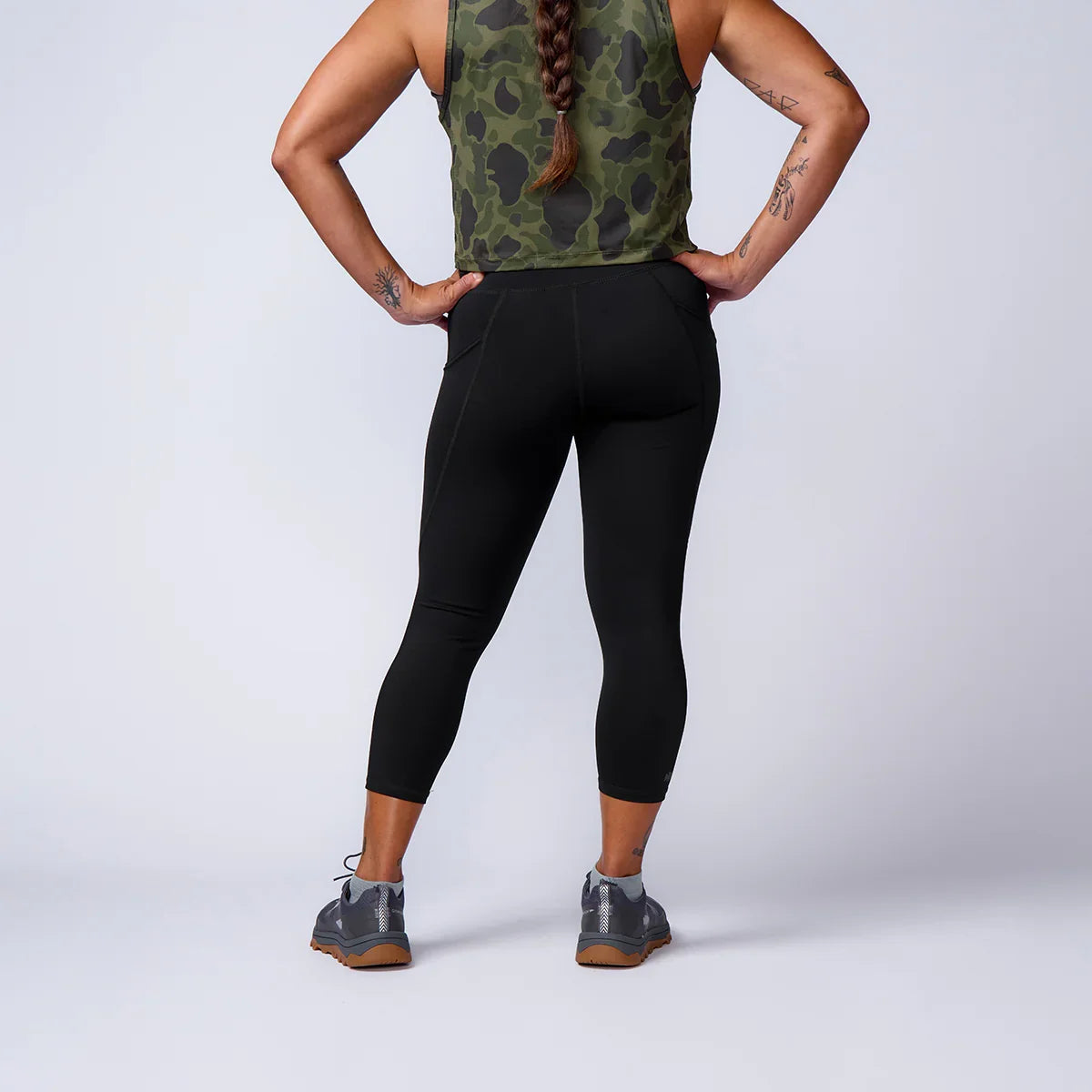 GORUCK athletic wear model in black leggings, camo tank, and rucking shoes, rear view