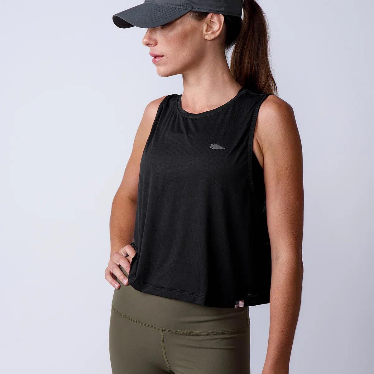 GORUCK women’s black tank top and olive leggings, athletic gear, studio background