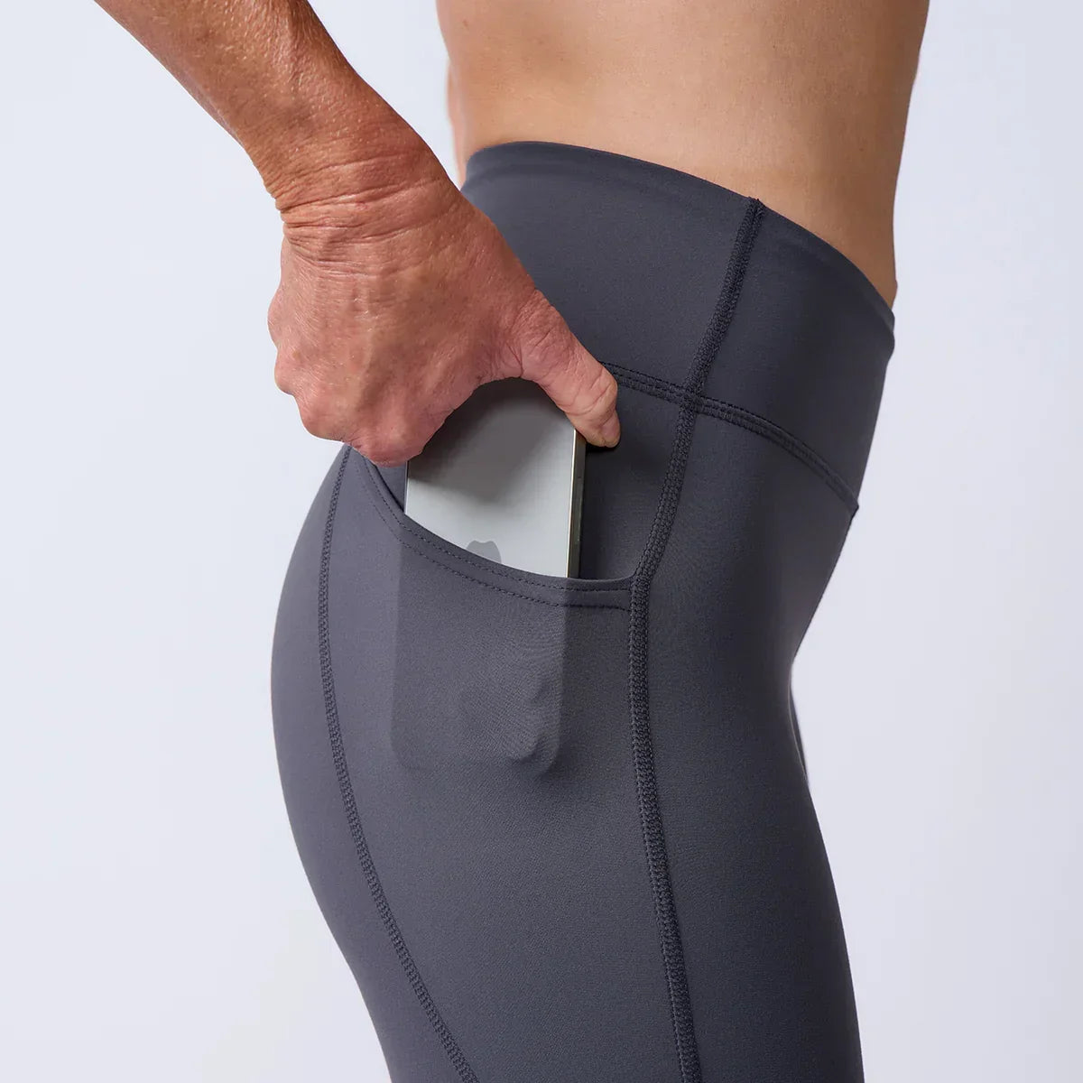 Close-up of a hand placing a phone into the side pocket of GORUCK rucking leggings