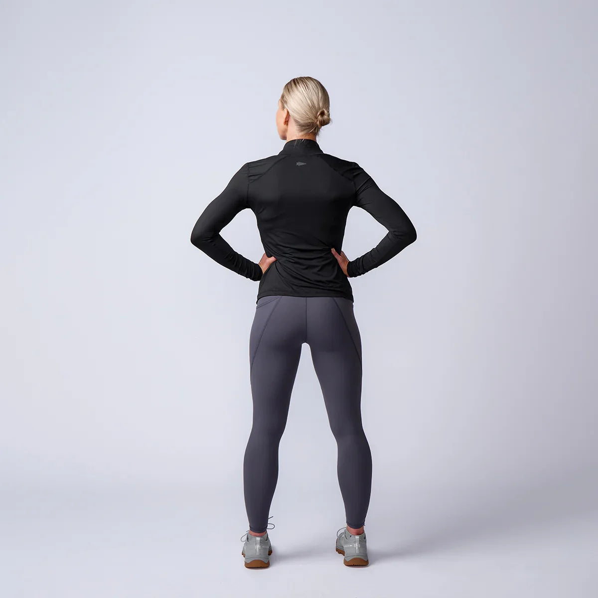 Woman wearing GORUCK rucking gear, black jacket and gray leggings in studio setting