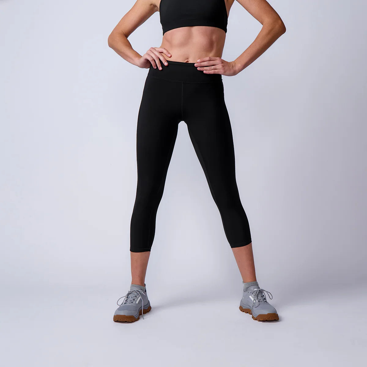 Woman modeling GORUCK black athletic leggings and gray rucking shoes in studio